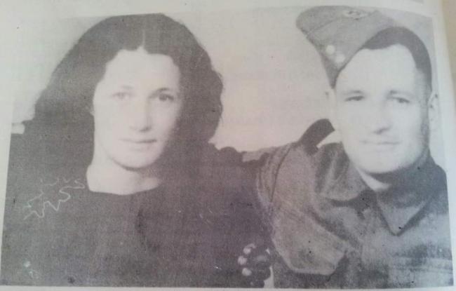 A soldier with one arm around a woman. 