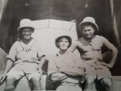Three soldiers in the back of a truck. 